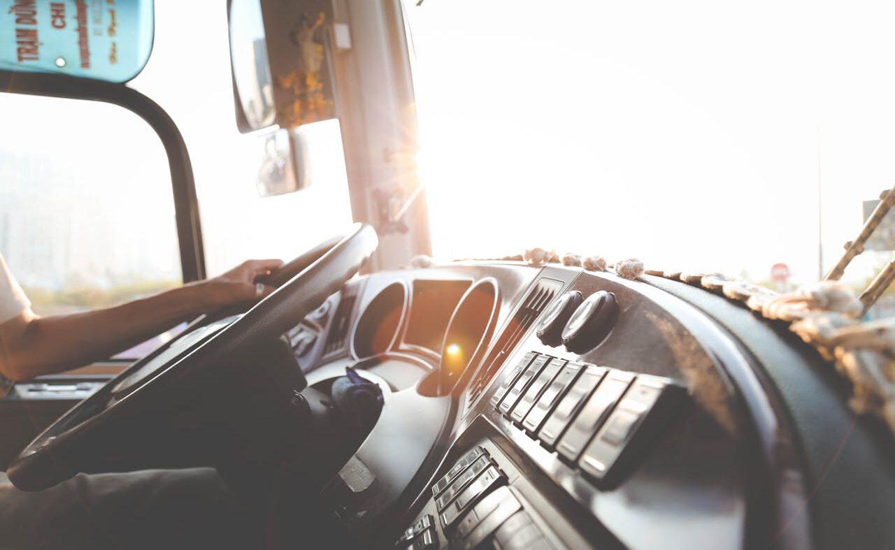 A bus driver navigating the city streets during a sunny day, focusing on the road.
