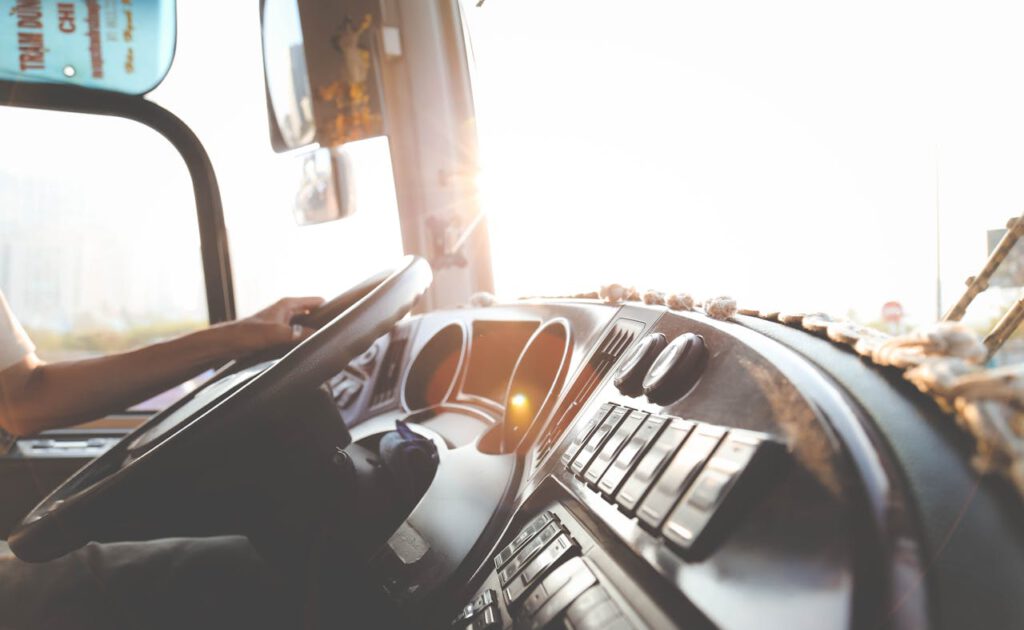 A bus driver navigating the city streets during a sunny day, focusing on the road.